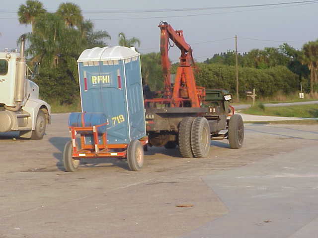 Loader pulling Porta Potty.